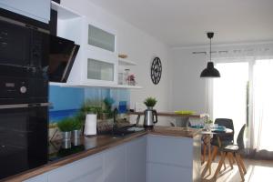 kuchnia z białymi szafkami i czarną kuchenką mikrofalową w obiekcie Apartamenty PatioHoliday w Jastrzębiej Górze