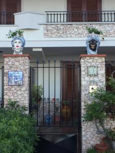 Una entrada a un edificio con una puerta con máscaras. en Colapesce, en Santa Teresa di Riva