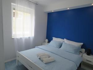 a blue bedroom with a white bed with a blue wall at Apartments Villa Urbajs in Vrsar