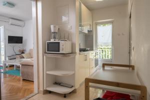 a kitchen with a microwave and a living room at Apartment Ema in Blace