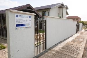 a gate in front of a house with a sign on it at PENSIUNEA AGROTURISTICA VALENTINO in Costinesti