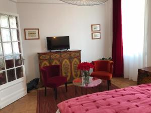 a bedroom with a bed and two chairs and a tv at Les Floralies Capucines in Marseille