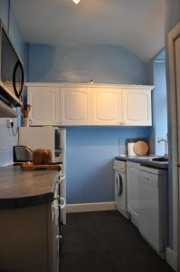 una cocina con armarios blancos y una pared azul en Auchmore Apartments, en Killin