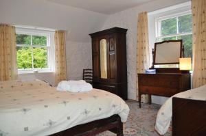 1 dormitorio con 2 camas, tocador y espejo en Auchmore Apartments, en Killin