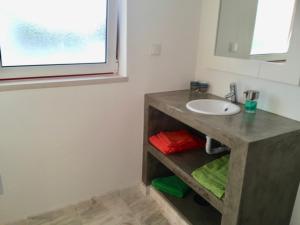 uma casa de banho com um lavatório e um espelho em Casa Oliveiras na Comporta