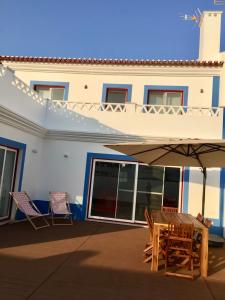 eine Terrasse mit 2 Stühlen, einem Tisch und einem Sonnenschirm in der Unterkunft Casa Oliveiras in Comporta