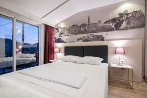 a bedroom with a large white bed with a painting on the wall at Casa Mia in Budva