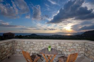 a table and chairs on a balcony with a sunset at Trochalo Villas 2 in Stoupa