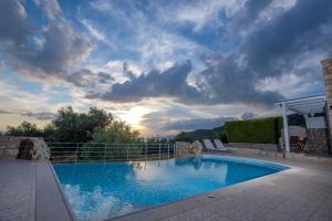 una gran piscina en un patio con un cielo nublado en Trochalo Villas 2, en Stoupa