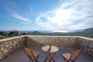 un patio con mesa y sillas en una pared de piedra en Trochalo Villas 2, en Stoupa