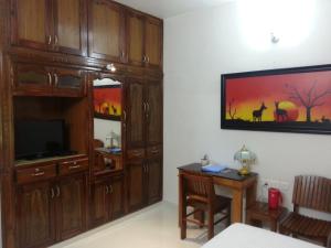 ein Wohnzimmer mit einem TV und einem Esstisch in der Unterkunft Belhaven Home Stay in Thiruvananthapuram