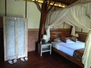 a bedroom with a bed with a canopy and two windows at Bali mountain forest cabin in Penebel