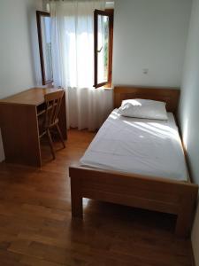 a bedroom with a bed and a desk and a window at Apartments Duka in Lumbarda