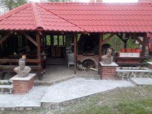 a gazebo with two statues and a dog under it at Casa DAOS in Nucşoara