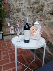 un tavolo bianco con una bottiglia di vino e due bicchieri di Casa Dalia a Montecatini Terme