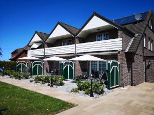 een gebouw met groene en witte deuren en parasols bij Haus Daniel in Neuharlingersiel