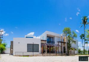 a white house with a palm tree in front of it at Home by the Bridge - SHA Certified in Kamphaeng Phet