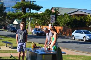 people standing around a table with a cake on it at La Costa Beachside Motel in Gold Coast