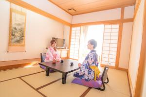 zwei Frauen in Kimonos, die an einem Tisch in einem Raum sitzen in der Unterkunft Yuzawa Grand Hotel in Yuzawa