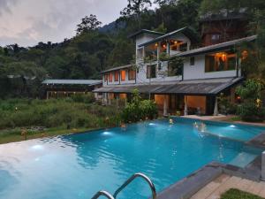 a villa with a swimming pool in front of a house at Sinharaja Forest Edge in Deniyaya