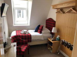 Un pequeño dormitorio con una cama y una silla. en Montague Guest House, en St Andrews