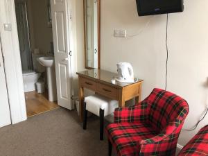 um quarto com uma mesa, uma cadeira e um espelho em Montague Guest House em St. Andrews