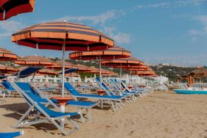 a bunch of chairs and umbrellas on a beach at Vasto Aparthotel in Vasto