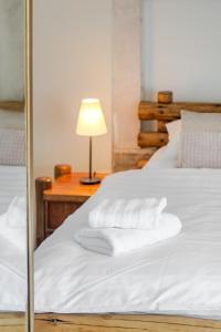 Una cama con sábanas blancas y una mesa con lámpara. en Casa Carminatti Apartments, en Split