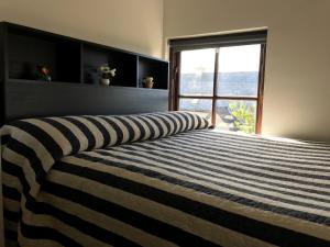 a bedroom with a striped bed with a large window at Heir Island House in Skibbereen