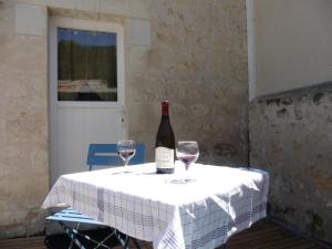 a bottle of wine sitting on a table with two glasses at Gîte Chemin des Prés r de Pré Vert in Chinon
