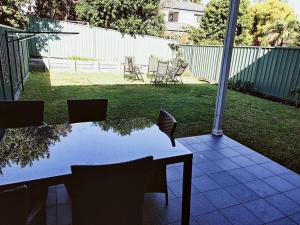 a table and chairs on a patio with a yard at Stylish Private Bathroom-Luxurious modern big home in Epping