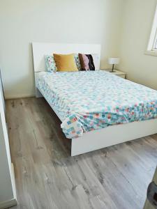 ein weißes Bett in einem Zimmer mit Holzboden in der Unterkunft Stylish Private Bathroom-Luxurious modern big home in Epping