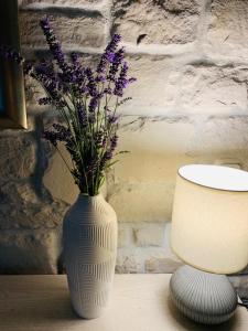a white vase with purple flowers in it on a table at Casa Maya apartment with private pool in Opatija