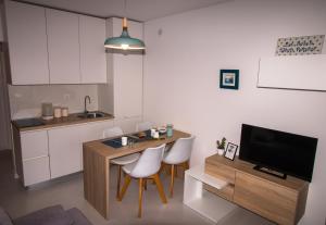 uma cozinha com uma mesa e cadeiras e uma televisão em Ceratonia Apartments em Lovište