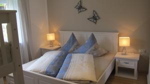 un letto con cuscini blu e bianchi e 2 lampade di Ferienhaus Windegge a Hirschegg