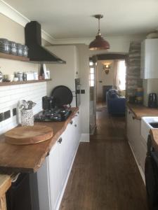 a kitchen with white cabinets and a wooden counter top at Bambu Cottage in Newquay