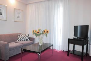 un soggiorno con divano e un vaso di fiori sul tavolo di Hotel Victory ad Atene
