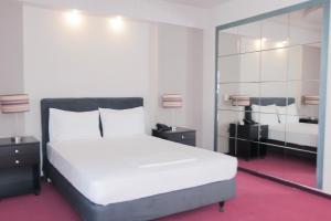 una camera da letto con un grande letto bianco e uno specchio di Hotel Victory ad Atene