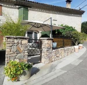 una casa con un muro di pietra e un ombrello di La maison de vos vacances a Claret