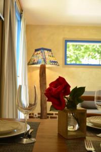 une table avec une rose rouge dans un vase sur une table avec une lampe dans l'établissement GITE "COTE JARDIN", à Vannecrocq