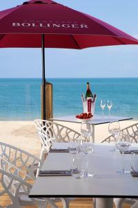 a table with wine glasses and an umbrella on the beach at The Boathouse in Carbis Bay