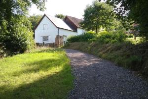 eine Schotterstraße vor einem weißen Haus in der Unterkunft Woodland Cottage in South Molton