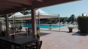 un patio con tavolo e sedie accanto alla piscina di Tenuta Agrituristica Castellesi a Squillace