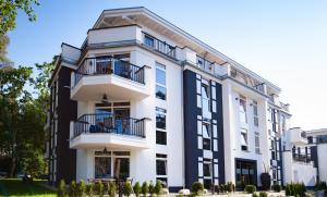 a large white building with balconies on it at Aparthotel Ostseeperle Glowe - schön gestrandet in Glowe