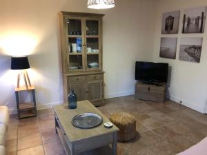 a living room with a table and a tv at Les Mésanges in Lamotte-Beuvron