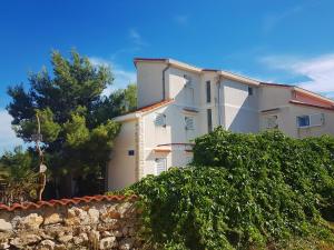 a large white house with a stone wall at Apartments Silver in Novalja