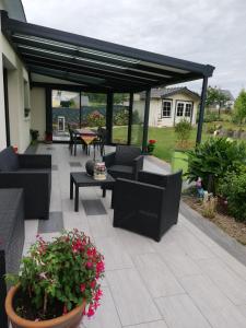 een patio met banken, tafels en bloemen bij Villa Lou Ann in Pontchâteau