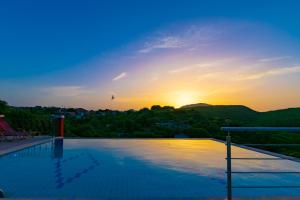 a swimming pool with the sunset in the background at Corfu Sokraki Villas in Sokrákion