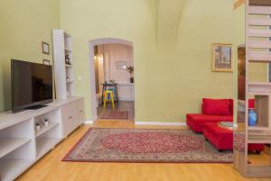 un soggiorno con divano rosso e TV a schermo piatto di City Light Apartment a Timişoara