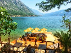 a group of tables and chairs with umbrellas on a lake at Apartments FANTASY in Kotor